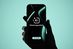 Ein Smartphone wird von einer Hand gehalten. Auf dem Display ist der Schriftzug "KI-Steuerungssystem" mit dem Zusatz "by conmeet" zu sehen. Der Hintergrund des Bildes ist in einem sanften, mintgrünen Farbton gehalten, der einen futuristischen Eindruck vermittelt. Die Darstellung des Smartphones und der Hand ist stilisiert, wobei die Hand in Schwarz gehalten ist, was einen starken Kontrast zum hellen Hintergrund bildet.