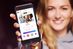 Eine junge Frau zeigt das Display ihres Smartphones. Darauf ist das Job-Game der Schul-App "scoolio" zu sehen. Auf digitalen Karten erhalten die Schülerinnen und Schüler einige Informationen zu Ausbildungsberufen. Auf diese Weise sollen sie die Berufswelt spielerisch kennenlernen.